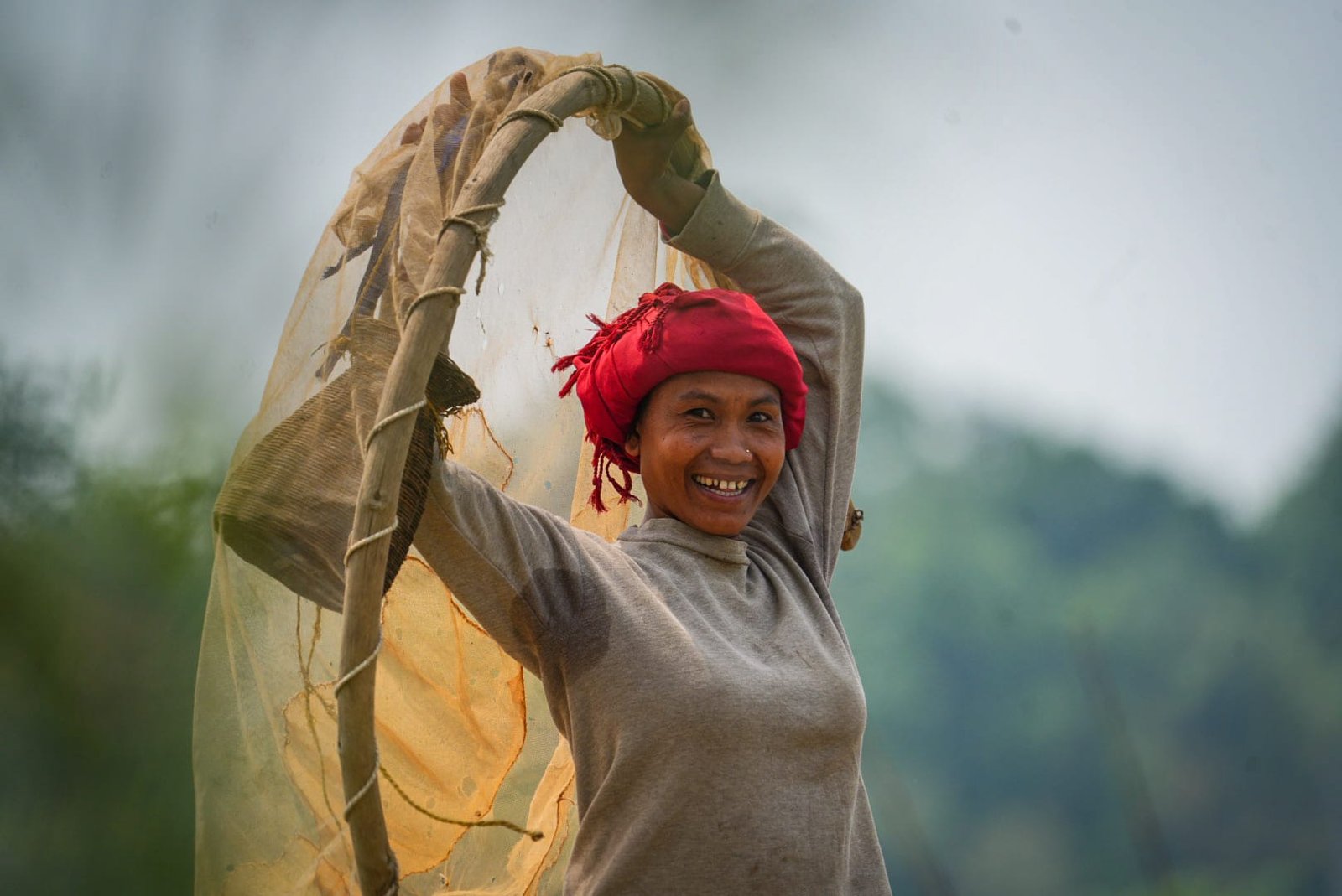 Sourire d'une femme Tharu pêchant au filet traditionnel dans les rivières du Terai au Népal